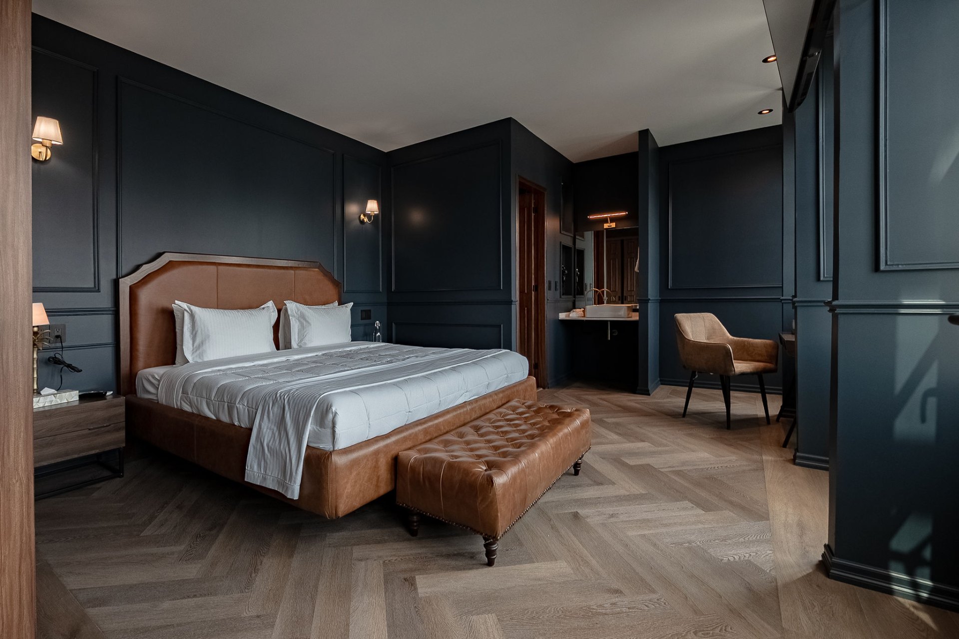 Suite boutique con paredes azul marino y cabecera de cuero